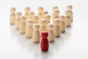 Diferentes peones de madera formados en triángulo, en el que el primero (vértice) es rojo y el resto color madera.